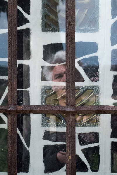 auto-portrait à l'ermitage de Saint Jean de Vareilles. Devant les barreaux personne, derrière les barreaux miroir de vitraux.